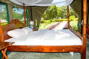 a bed in a tent in a field of flowers at Giraffe Hills Mara Camp in Ololaimutiek