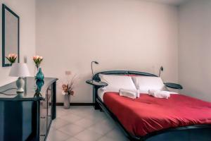 a bedroom with a bed with red sheets and a table at Fronte Ospedale, Parcheggio Gratis e Centro vicino in Piacenza