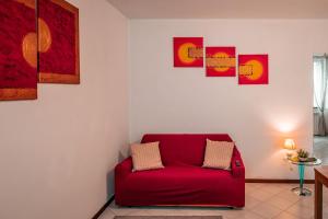 a red couch in a room with pictures on the wall at Fronte Ospedale, Parcheggio Gratis e Centro vicino in Piacenza +1 photo