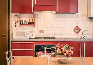a kitchen with red cabinets and a table with a vase of flowers at Fronte Ospedale, Parcheggio Gratis e Centro vicino in Piacenza