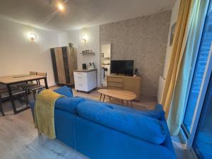 a living room with a blue couch and a table at La cachette audomaroise avec sa terrasse in Saint-Omer