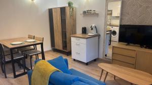 a living room with a blue couch and a kitchen at La cachette audomaroise avec sa terrasse in Saint-Omer