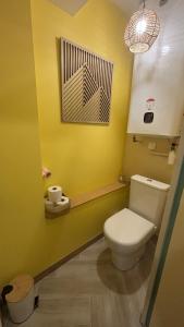 a bathroom with a white toilet and a yellow wall at La cachette audomaroise avec sa terrasse in Saint-Omer