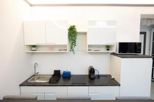 a kitchen with white cabinets and a black counter top at White Titanic 322 in Mamaia Nord