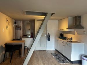 a kitchen with white cabinets and a table and a staircase at Garden house, Free parking in Zandvoort