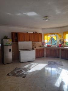 a kitchen with wooden cabinets and a white refrigerator at Jamaica Villa Sweetsop & Tours in Montego Bay