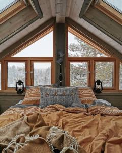 a bedroom with a large bed in front of windows at Faråsen Luxury Treetop Cabin - Sleep Among the Trees in Ringsaker