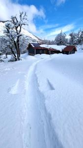 a snow covered field with a house in the background at Casa en Lago Hermoso sobre Laguna Cristalina con Muelle Privado in San Martín de los Andes +69 photos