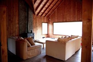 a living room with two couches and a table at Casa en Lago Hermoso sobre Laguna Cristalina con Muelle Privado in San Martín de los Andes