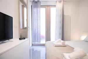 una camera da letto bianca con TV e ampia finestra di Affittacamere - Rosa dei venti a Porto SantʼElpidio