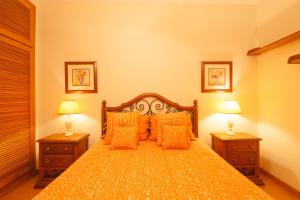 a bedroom with a bed with orange pillows and two lamps at Oceanos premium apartment in Ovar