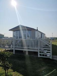 a house with a white porch and a fence at Millfield caravan site, caravan L6 in Ingoldmells
