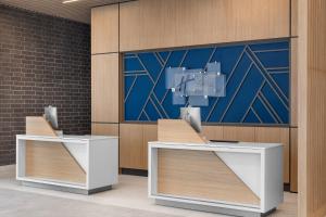 two reception desks in a lobby with a painting at Holiday Inn Express Montreal Airport - St-Laurent by IHG in Montréal