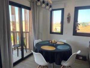 a dining room with a table and chairs and windows at F3 à mimizan plage in Mimizan-Plage