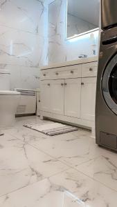 Un baño blanco con lavabo y lavadora. en Cozy Terrebonne, en Terrebonne