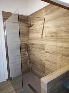 a shower with a wooden wall and a glass door at Gîte-Love Room L'Albizia - Escapade romantique in Bindernheim