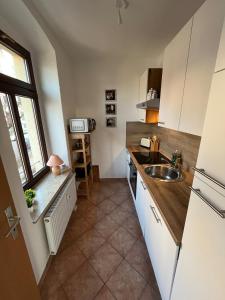 a kitchen with white cabinets and a sink and a window at FeWo Blick zum Lulatsch in Chemnitz