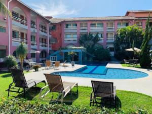 a resort with a pool and chairs and a building at Hotel Brisa da Costa in Macaé