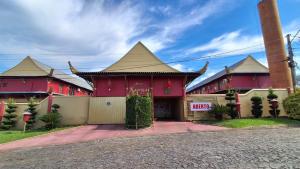 a red building with a pointed roof at Xangai Motel by Drops in São Leopoldo