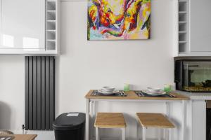 eine Küche mit einem Tisch mit 2 Stühlen und einem Gemälde in der Unterkunft Townhouse with modern mobility accessible apartment including widened doors and ramps, pets welcome, 5 bedrooms, secure off road parking, near Home Park, golf, pitch and putt, tennis courts, Argyle, eateries, microbrewery, pubs, boutique shops and salons in Plymouth