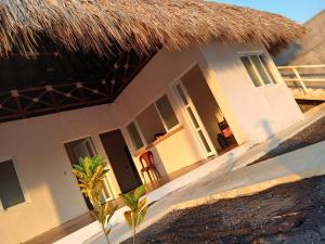 a house with a thatched roof and a palm tree at Villa Sanyolí in La Barrita