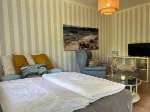 a bedroom with a bed and a chair and a tv at Wieck - Ferienwohnung EVA & HANSI by Restaurant WIESENAU in Wieck