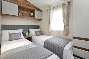 two beds in a small room with a window at Lakeside Retreat - AGH Hot Tub Breaks - Tattershall Lakes in Tattershall