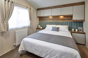 a bedroom with a large white bed and a window at Lakeside Retreat - AGH Hot Tub Breaks - Tattershall Lakes in Tattershall