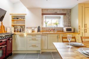 a kitchen with white cabinets and a wooden table at Luxurious Cosy Cottage in Buxton +29 photos