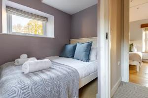 a bedroom with a bed with blue pillows and a window at Luxurious Cosy Cottage in Buxton