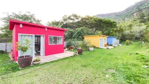 una casita roja y amarilla en un patio en Rubi, en São Pedro