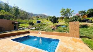 a swimming pool with a water fountain in a yard at Chácara Itaqueri Rubi in São Pedro