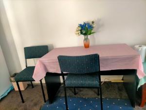 a table with two chairs and a vase of flowers on it at Maha Melton Homestay in Melton South