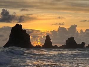 a sunset over the ocean with rocks in the water at Kay Soley La in Saint-François