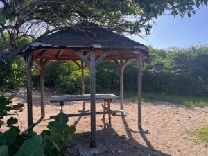 a picnic shelter with a bench in the dirt at Kay Soley La in Saint-François