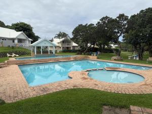 a large swimming pool in a yard with a house at 26 Montego Bay at Caribbean Estates in Port Edward