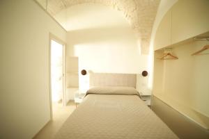 a white bedroom with a bed and a window at Suite centro storico in Locorotondo