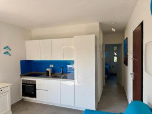 a kitchen with white cabinets and a blue wall at Appartamenti delfini terza spiaggia in Golfo Aranci
