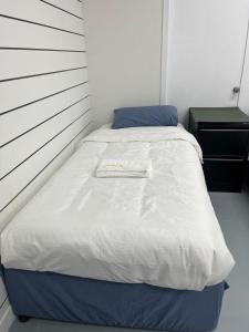 オークランドにある3 single bed and 2 double sofa beds Serviced Studio, Suite 7の白いベッドバイザー付きの客室のベッド1台分です。