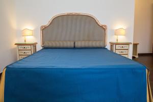 a blue bed with two nightstands and two lamps at La Rada B&B in Bacoli