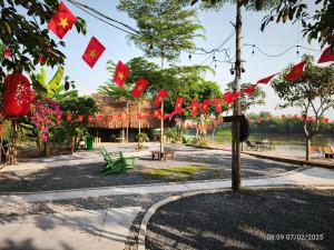 un parque con banderas chinas rojas, mesas y bancos en Homestay Mẹ khang 2 - Room lake view, en Cu Chi 1 foto más