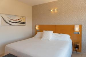 a bedroom with a white bed with a wooden headboard at La Sort Boutique Hotel in Moraira