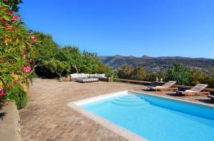 a swimming pool in a yard with mountains in the background at Aegean Bliss Villa - Hydroussa in Andros