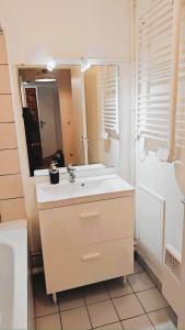 Un baño blanco con lavabo y espejo. en Mini-studio avec kitchenette OU chambre confort avec frigo et TV - Parking en option sur résa !, en Chaville