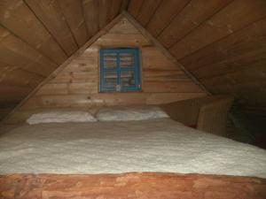 a bed in a log cabin with a window at Holiday Park Zelenkovac in Podrašnica