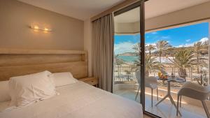 a bedroom with a bed and a balcony with a table at La Sort Boutique Hotel in Moraira
