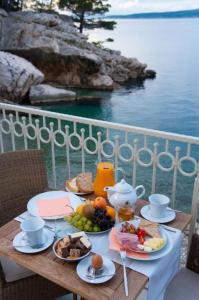 a table with breakfast food on a balcony overlooking the water at Apartments and Room Luxury dream in Brela