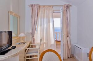 a room with a desk with a television and a balcony at Apartments and Room Luxury dream in Brela