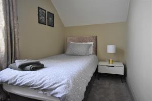 a bedroom with a bed and a side table with a lamp at Central Cheerful Comfortable 3 Bedroom Home in Pallion