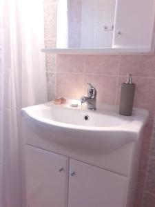 a bathroom with a white sink and a mirror at Stavento Apartments in Aliki